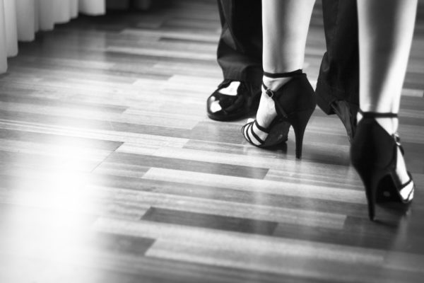 Male and female ballroom, standard, sport dance, latin and salsa couple dancers feet and shoes in dance academy school rehearsal room dancing salsa.